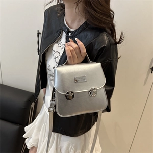 Metallic silver mini bucket bag with adjustable straps shown by a model in black leather jacket