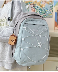 Vue latérale d'un sac à dos scolaire bleu clair et gris avec cordons et pendentif peluche