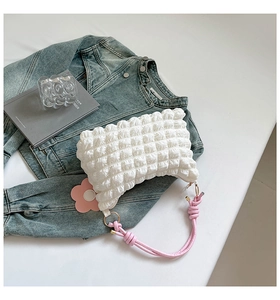 Detailed view of white bubble texture bag with pink knotted handle and floral charm