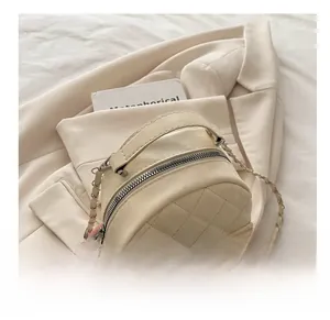 Close-up of beige quilted mini backpack with metallic chain and silver twist lock