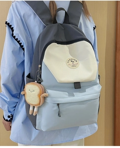 Close-up of color-block nylon backpack with fashion embroidery and cute plush pendant