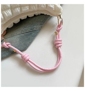 Detail of cream bubble texture shoulder bag with pink knotted strap and gold hardware