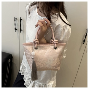 Detail of light pink bucket bag with landscape embroidery and elegant grey tassel