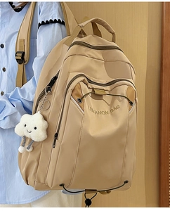 Detail view of large beige nylon backpack with embroidery and cloud plush charm