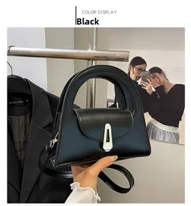 Detail einer schwarzen Lederhandtasche mit Trapezform und silbernem Metallverschluss