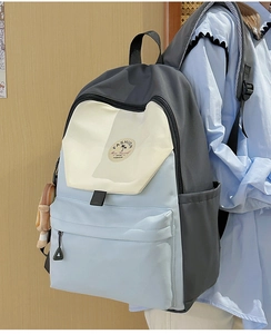 Detail of color-block nylon backpack with side pockets and cute plush pendant