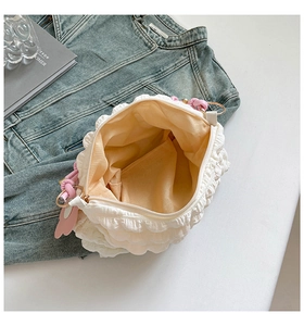Detailed macro view of white pleated fabric shoulder bag with pink heart charm and zip