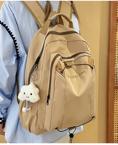 Close-up of beige nylon backpack featuring LUKANON BAG embroidery and cloud plush charm