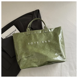 Détail d'un cabas vert brillant texturé avec inscription TOTE BAG et fini laqué