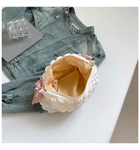 Top view of white bubble cloud bag with gold zipper and pink knot charm detail