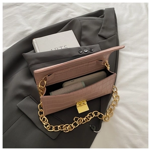Dettaglio borsa rosa stampa coccodrillo con catena dorata su sfondo blazer grigio