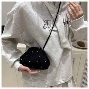 Detail view of a black floral crossbody cloud bag with a slim strap worn by a model