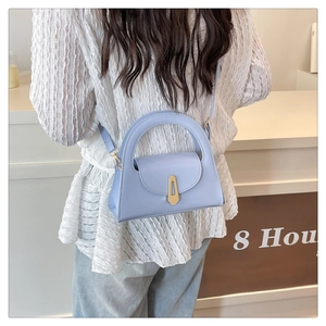 Detail of light blue crossbody bag with gold buckle and adjustable strap on a model