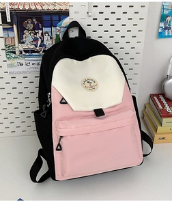 Detail of color-block canvas backpack featuring embroidery patch and front pocket
