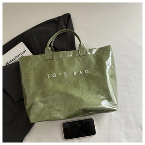 Détail d'un cabas vert brillant avec texte blanc sur fond de costume d'affaires chic