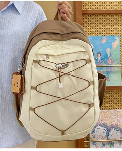 Vue détaillée d'un sac à dos beige et marron avec pendentif toast et cordons élastiques