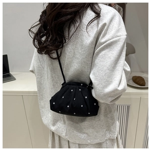 Detail of black mini pleated crossbody bag with white floral pattern on a casual outfit