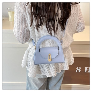 Detail view of light blue small tote bag with gold buckle on a crossbody model