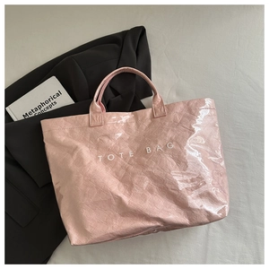 Gros plan d'un sac cabas rose brillant avec texture froissée et logo blanc sur tissu