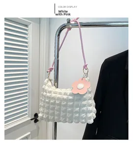 Detail view of white ruched shoulder bag with pink floral pendant and zip closure