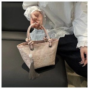 Detailed close-up of pink oriental jacquard bucket bag with tassels and embroidery