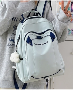 Close-up of light blue waterproof backpack with plush cloud pendant and side pocket detail