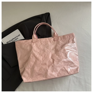 Détail d'un sac cabas rose brillant avec texture froissée et poignées élégantes