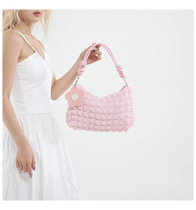 Detailed view of pink bubble textured shoulder bag with floral charm and soft handle