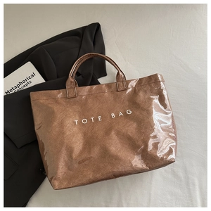 Vue détaillée du revêtement PVC brillant imperméable sur le sac cabas marron minimaliste