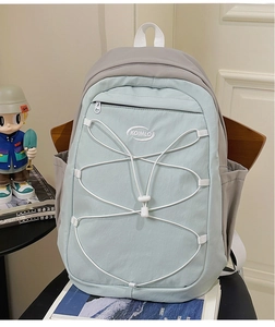 Détail du sac à dos en nylon vert menthe et gris avec cordons élastiques sur une chaise