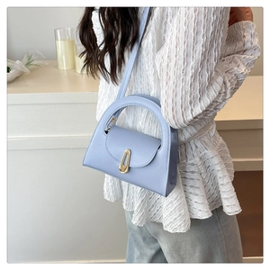 Detail of light blue semi-circular handbag with golden lock and curved handle