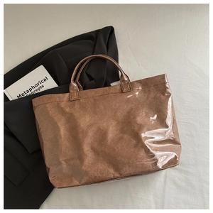 Vue détaillée du cabas marron brillant sur tissu beige avec accessoires de mode chic