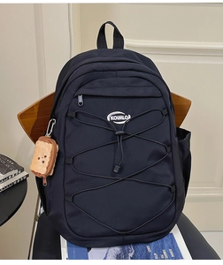Détail du sac à dos en nylon noir avec cordons élastiques et breloque toast