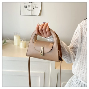 Detailed view of the earth-tone leather handbag with a unique metal lock and handle