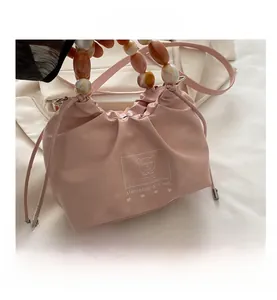 Detail of pink drawstring bucket bag featuring amber acrylic bead handle and teddy bear print