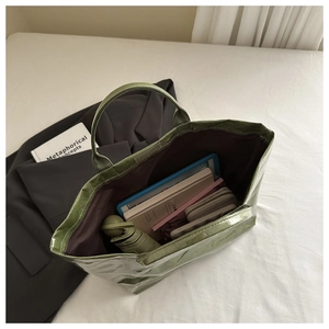 Détail intérieur du grand sac cabas vert contenant une tablette, parapluie et portefeuille