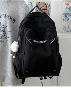 Detail of large black nylon backpack featuring embroidery and plush cloud keychain