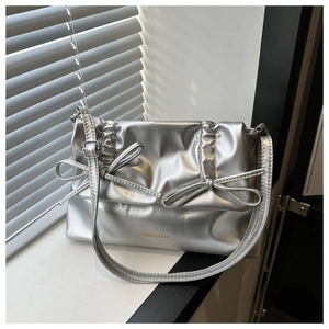 Details einer silbernen Metalltasche mit horizontalen Falten und Schleifen auf Fenster