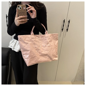 Détail d'un sac cabas rose brillant froissé avec impression TOTE BAG blanche style quotidien