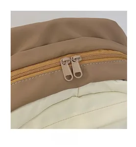 Détail de la fermeture à double glissière sur un sac à dos en nylon beige bicolore