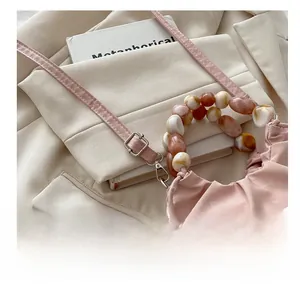 Detail of pink pleated bucket bag featuring marble-textured beads and adjustable strap buckle