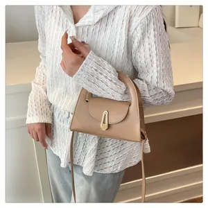 Detail showing beige crossbody bag with gold geometric buckle and leather strap