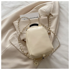 Detail eines beigen Stepp-Rucksacks mit schwarzem Griff und Metall-Kettenriemen