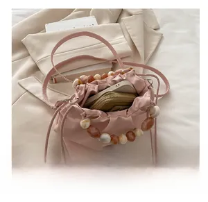 Pink satin bucket bag with drawstring showing interior capacity for phone and wallet
