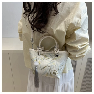 Detail of embroidered bucket bag featuring elegant leaf patterns and tassel decoration