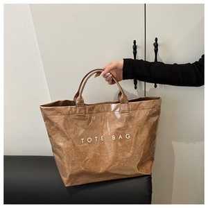 Détail du cabas en papier marron avec housse en PVC étanche et lettrage blanc TOTE BAG