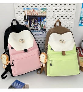 Detail of color-block nylon backpacks with cute bread plush charms and front zip pocket