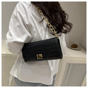 Dettaglio borsa a spalla nera coccodrillo con catena dorata indossata da una modella