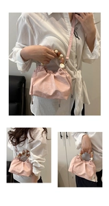 Detail of light pink drawstring bag featuring a glossy finish and beaded top handle
