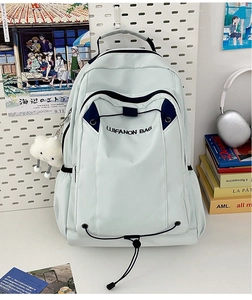 Detail of light blue backpack with drawstring closure and white cloud plush charm